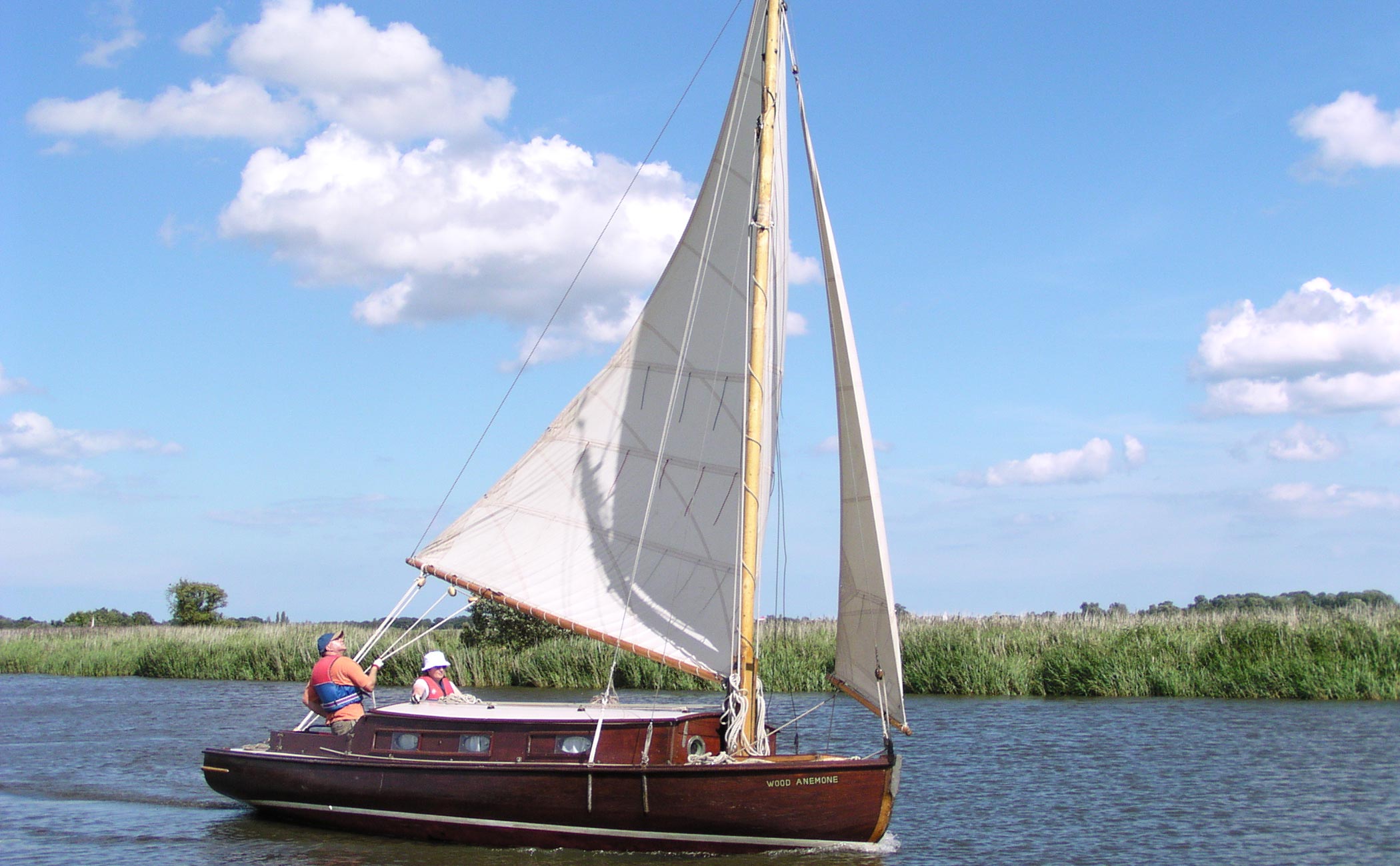 Traditional wooden Wood class cabin yacht sailing on the Norfolk Broads
